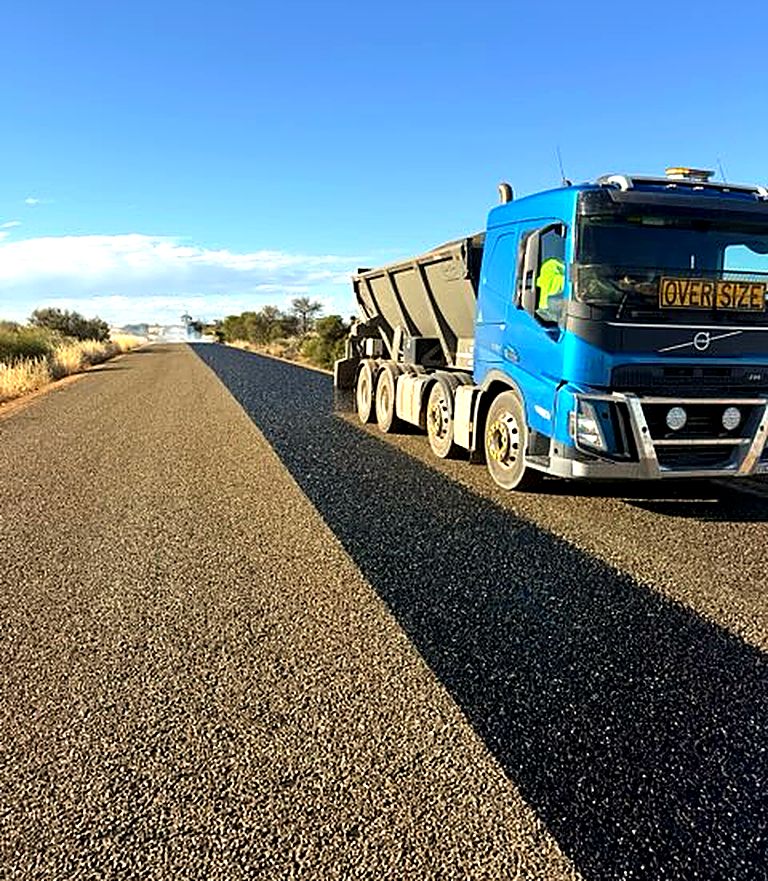 WA Sprayseal Volvo live-bottom aggregate truck on a freshly sealed road