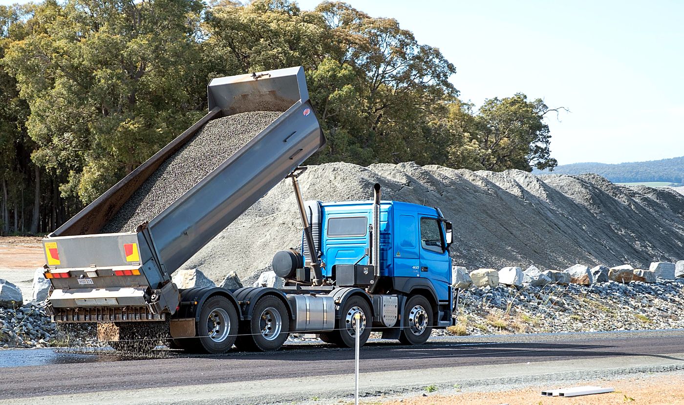 Aggregate truck spreading stone onto a fresh seal